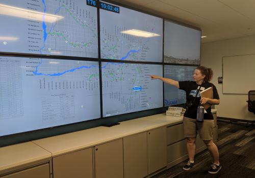 Photo of teacher pointing out to monitoring system screen at SRP facility